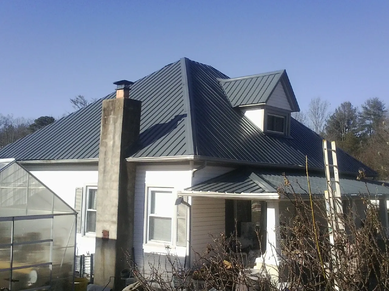 Dark blue standing seam metal roof on a white farmhouse with dormer — Slate & Tile Roof Repair by Roofing Brothers in Caneyville