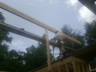 Carpenter setting a ridge beam over a new addition frame — Ice Dam Removal by Roofing Brothers in Caneyville