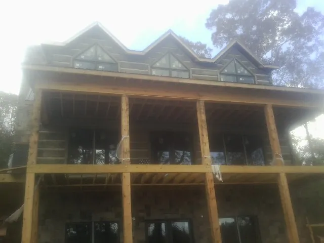 Dormers and porch framing on a large log home under construction — Roof Coating work by our crew in Caneyville