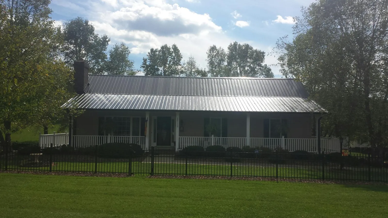 Gray metal roof on a brick ranch with a full width front porch — Gutter Guard Installation work by our crew in Caneyville