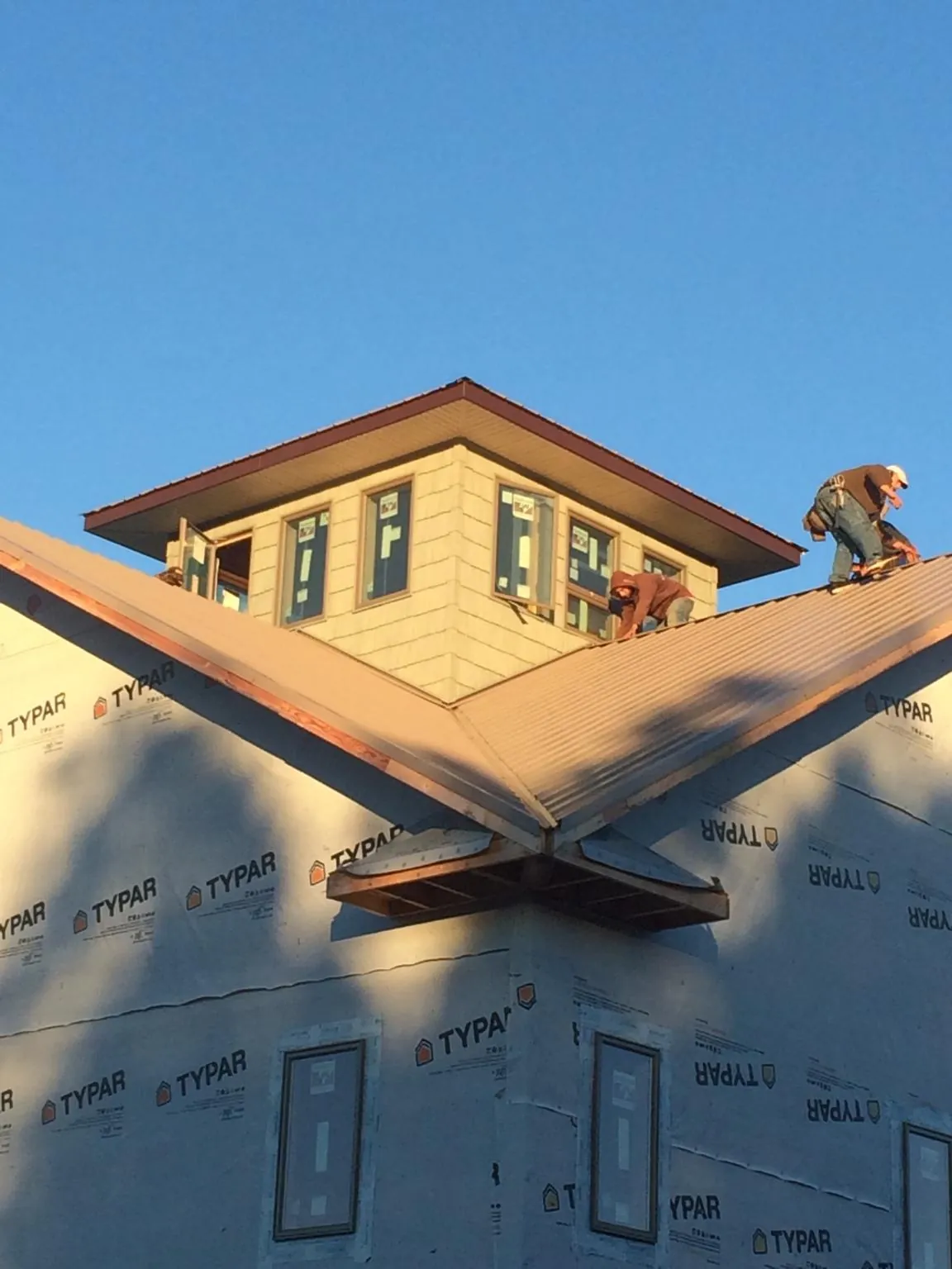 Roofers working around a rooftop cupola on a new metal roof at sunset — Roof Waterproofing in Caneyville by Roofing Brothers